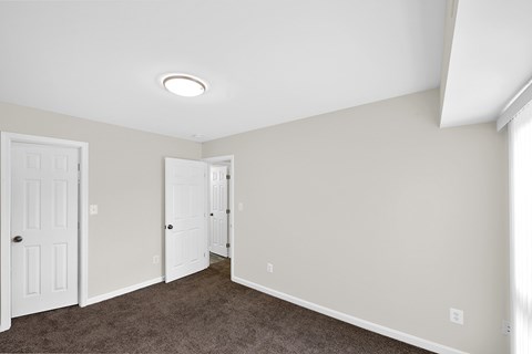 an empty room with a carpeted floor and white doors